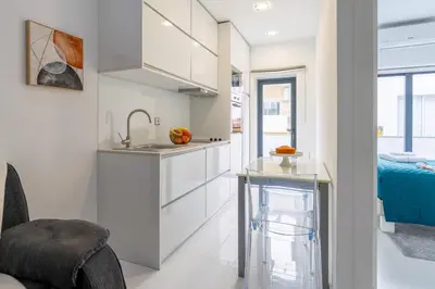 a kitchen with white cabinets and a sink and a bed at Sleek Apartment with Balcony by HostWise in Porto