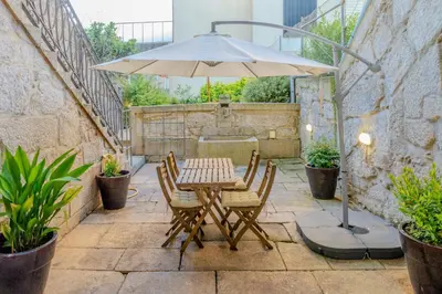 a table and chairs with an umbrella on a patio at VIVA República Serviced Apartment in Porto