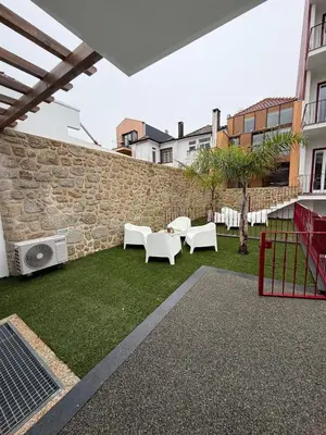 a courtyard with white chairs and a stone wall at Pinheiro Houses's- Luxury Apartment's by Oporto Soul in Porto
