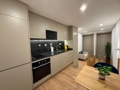 a kitchen with white cabinets and a table and a dining room at Pinheiro Houses's- Luxury Apartment's by Oporto Soul in Porto