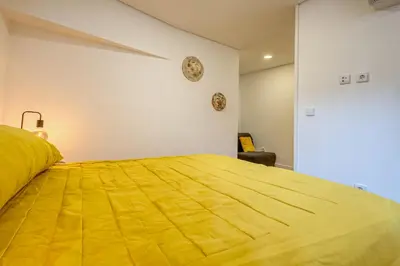 a bedroom with a large yellow bed with a clock on the wall at OPORTO GUEST São Brás 66 in Porto