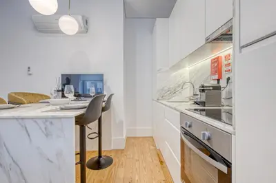 a kitchen with white countertops and a table with a chair at OPORTO GUEST São Brás 66 in Porto
