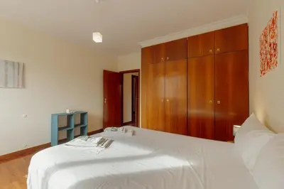 a bedroom with a white bed with a wooden cabinet at Botanic Garden Terrace Apartment by Vacationy in Porto