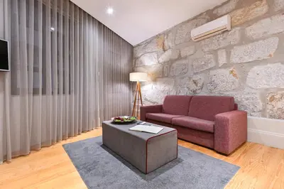 a living room with a red couch and a stone wall at ON Apartments - Free Parking & Pet Friendly in Porto