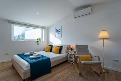 a bedroom with a bed and a chair and a window at Oporto Nura House Duplex Downtown in Porto