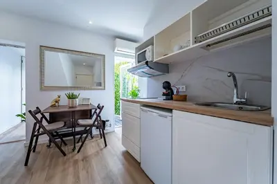 a kitchen with white cabinets and a table and a sink at Oporto Nura House Duplex Downtown in Porto