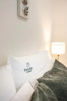 a white bed with a pillow with a logo on it at Gloria in Porto - Porto Velho Apt in Porto