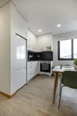 a kitchen with white cabinets and a table at Gloria in Porto - Porto Velho Apt in Porto