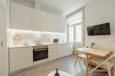 a kitchen with white cabinets and a wooden table at Downtown Cosy Apartment by Vacationy in Porto