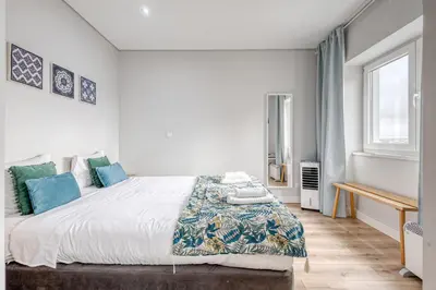 a white bedroom with a large bed with blue pillows at Oporto Guest Green Flat in Porto