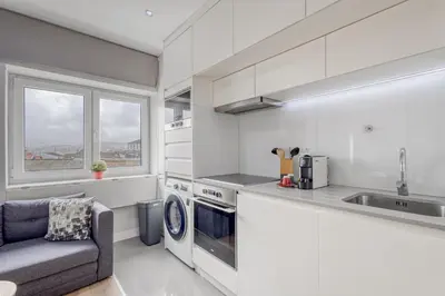 a kitchen with white cabinets and a sink and a couch at Oporto Guest Green Flat in Porto