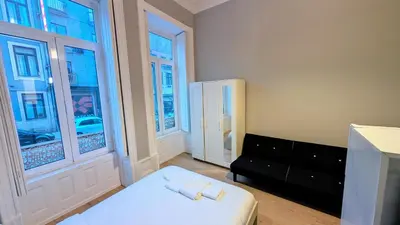 a bedroom with a bed and two windows at Riko Guest House 2 in Porto