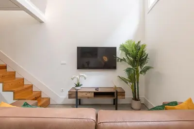 a living room with a couch and a tv on a wall at Design loft, Downtown Porto in Porto