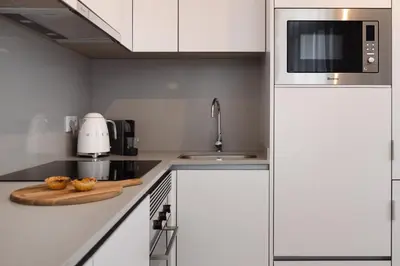 a kitchen with white cabinets and a microwave at Ribeira Apartments Flores in Porto