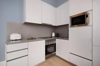 a white kitchen with white cabinets and a microwave at Ribeira Apartments Flores in Porto