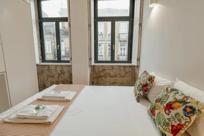 a bedroom with a bed with two tables and two windows at Bonfim 362 by Vacationy in Porto