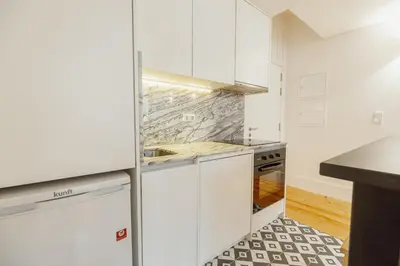 a kitchen with white cabinets and a black and white tile floor at Bonfim 362 by Vacationy in Porto