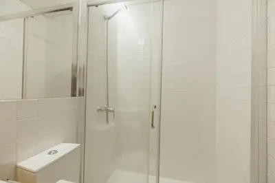 a shower with a glass door next to a toilet at Bonfim 362 by Vacationy in Porto