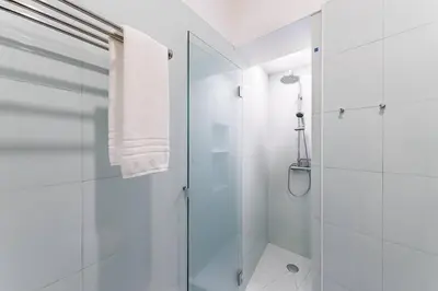 a white bathroom with a shower with a glass door at Cantinho do Porto - Metro 1 Minute Away in Porto