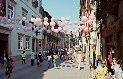 a group of people walking down a street with pink balloons at Porto Pacific - Rua das Flores - Flower Street in Porto