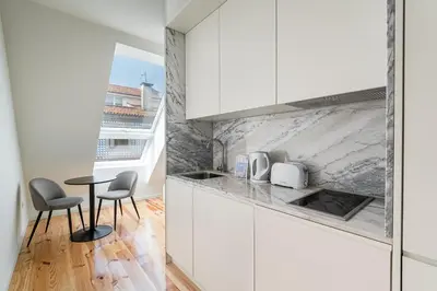 a kitchen with white cabinets and a table and chairs at GuestReady - Urban retreat in Boavista in Porto