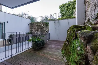 a wooden walkway next to a rock wall at Cosy Flat in Porto with Private Patio & Garden Area by Lisbeyond in Porto