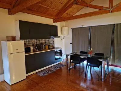 a kitchen with a white refrigerator and a table with chairs at Estúdio na Estação in Porto