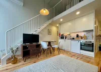 a kitchen with a table with a television and a staircase at Terrace Loft near Porto Center in Porto