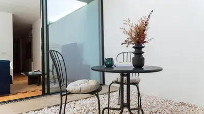 a table with two chairs and a vase with flowers at Ando Living - São Miguel House in Porto
