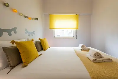 a bedroom with a large white bed with yellow pillows at GuestReady Essential - Heartbeats in Porto