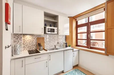 a kitchen with white cabinets and a sink and a window at D&S - Porto São Bento Apartments in Porto
