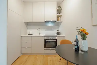 a kitchen with white cabinets and a table with flowers at Bright Window Apartment by Vacationy in Porto