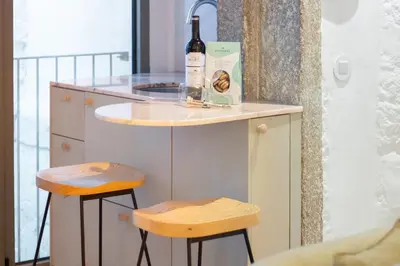 a bottle of wine sitting on a counter with two stools at Bainharia 82 by LovelyStay in Porto