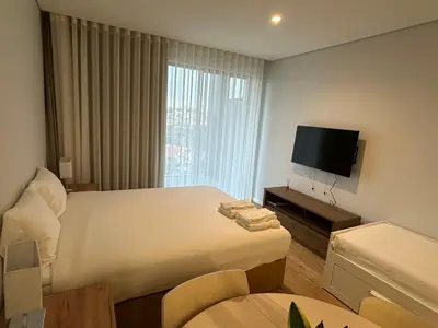 a hotel room with a bed and a flat screen tv at New Douro Tower 203 With Parking in Vila Nova de Gaia