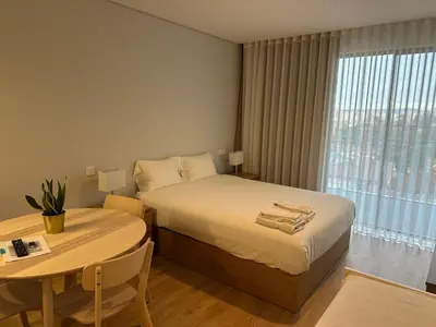 a bedroom with a bed and a table and a window at New Douro Tower 203 With Parking in Vila Nova de Gaia