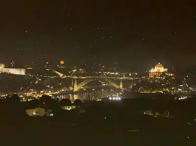 a view of a city at night with a bridge at New Douro Tower 206 with shared pool and parking in Vila Nova de Gaia