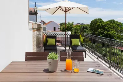 a table with two glasses and an umbrella on a balcony at BO - Marquês Apartments in Porto