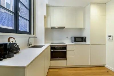 a kitchen with white cabinets and a sink and a microwave at GuestReady - Peaceful haven in Porto in Porto