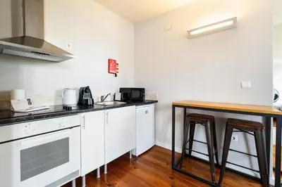 a kitchen with white cabinets and a wooden table at GuestReady - Cosme Heritage Apartments in Porto