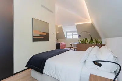 a bedroom with a large white bed and a table at Bolhão Luxury Apartments in Porto