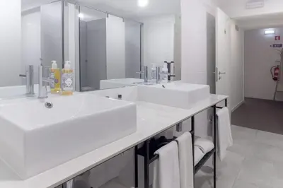 a white bathroom with two sinks and a mirror at Magnolia - Exclusive Garden Apartment in Porto