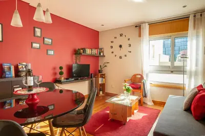 a living room with a table and a red wall at Francos Relaxing Apartment by the metro in Porto