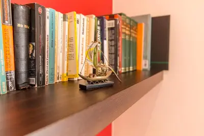 a smallclock sitting on a shelf in front of books at Francos Relaxing Apartment by the metro in Porto