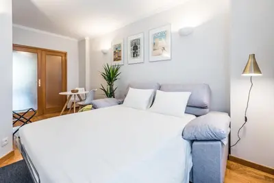 a bedroom with a white bed and a blue couch at GuestReady - Charming Cozy Getaway in Porto in Porto