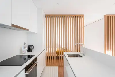 a kitchen with white counters and a wooden partition at GuestReady - One perfect home near Marquês in Porto