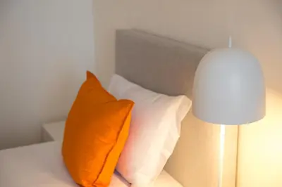 an orange pillow sitting on a bed next to a lamp at GuestReady - Porto stay with outdoor charm in Porto