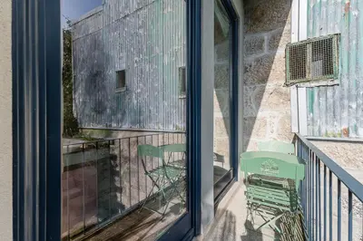 a balcony with a green chair and a window at GuestReady - Urban paradise in Porto in Porto