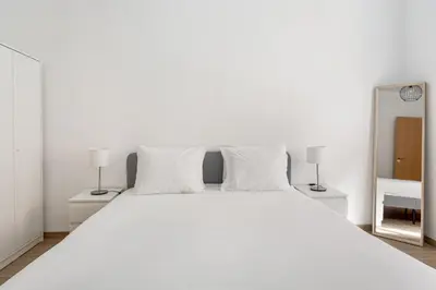 a white bed with two lamps and a mirror at GuestReady - Central & spacious apartment in Porto in Porto