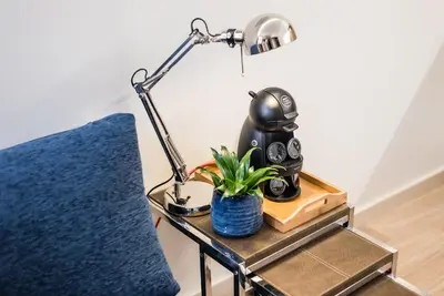 a lamp and a plant on a table next to a chair at GuestReady - Timber-framed luxe stay in Porto
