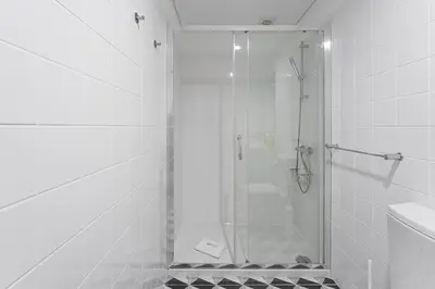 a white bathroom with a shower and a sink at GuestReady - Cheerful place in Porto in Porto